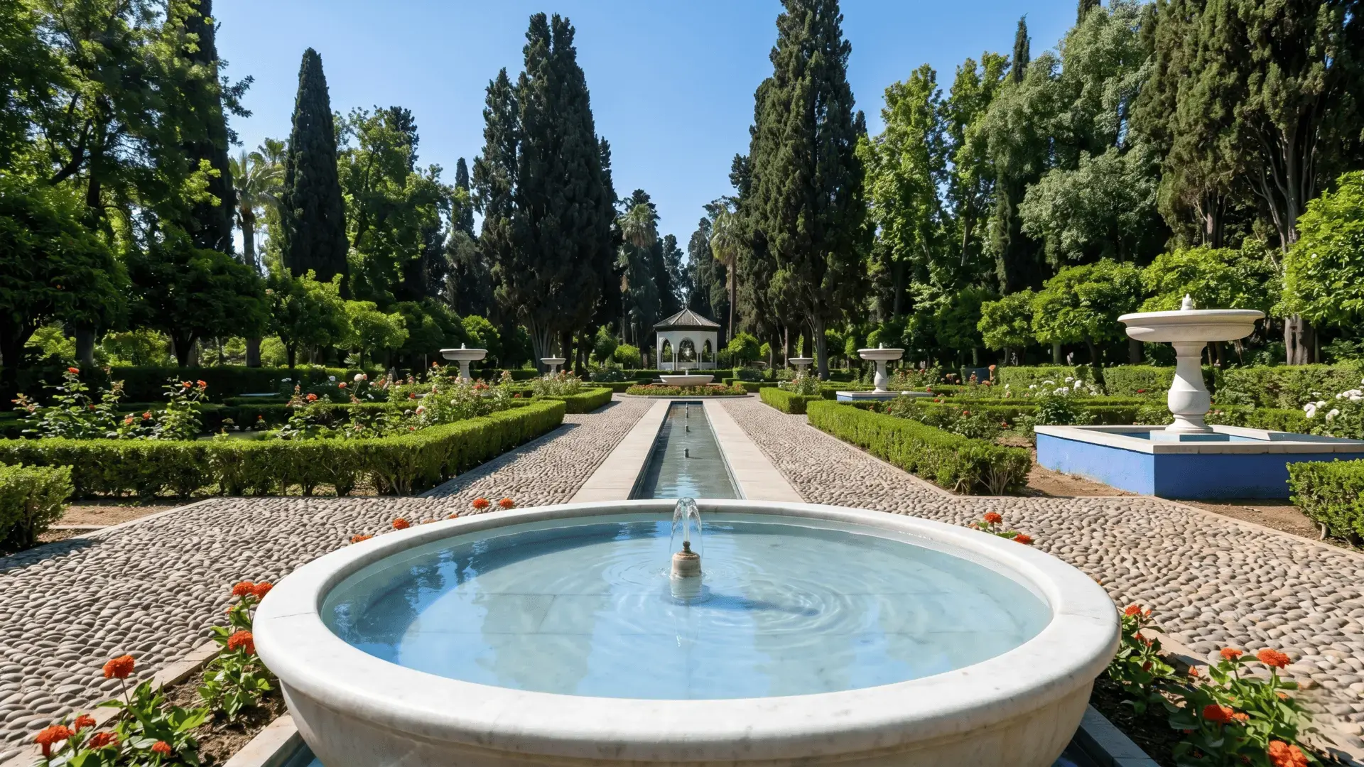 Peaceful fountain in Jnan Sbil Gardens Fez Morocco with symmetrical hedges, roses, tall cypress trees, and a historic pavilion under blue sky