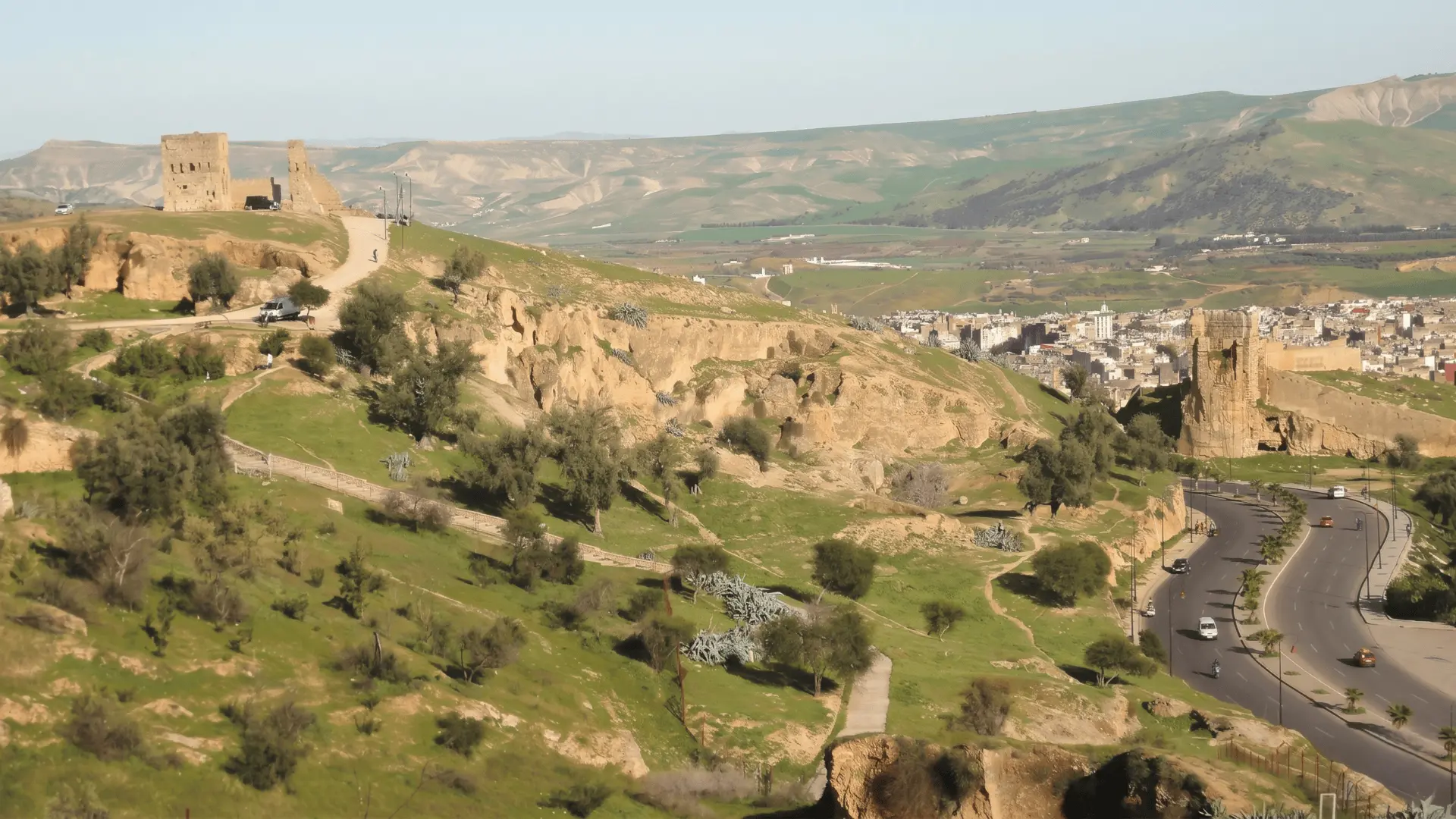 Wide landscape view from Marinid Tombs overlooking Fez Medina with ancient ruins, hills, and cityscape — iconic entrance panorama to Fez Morocco