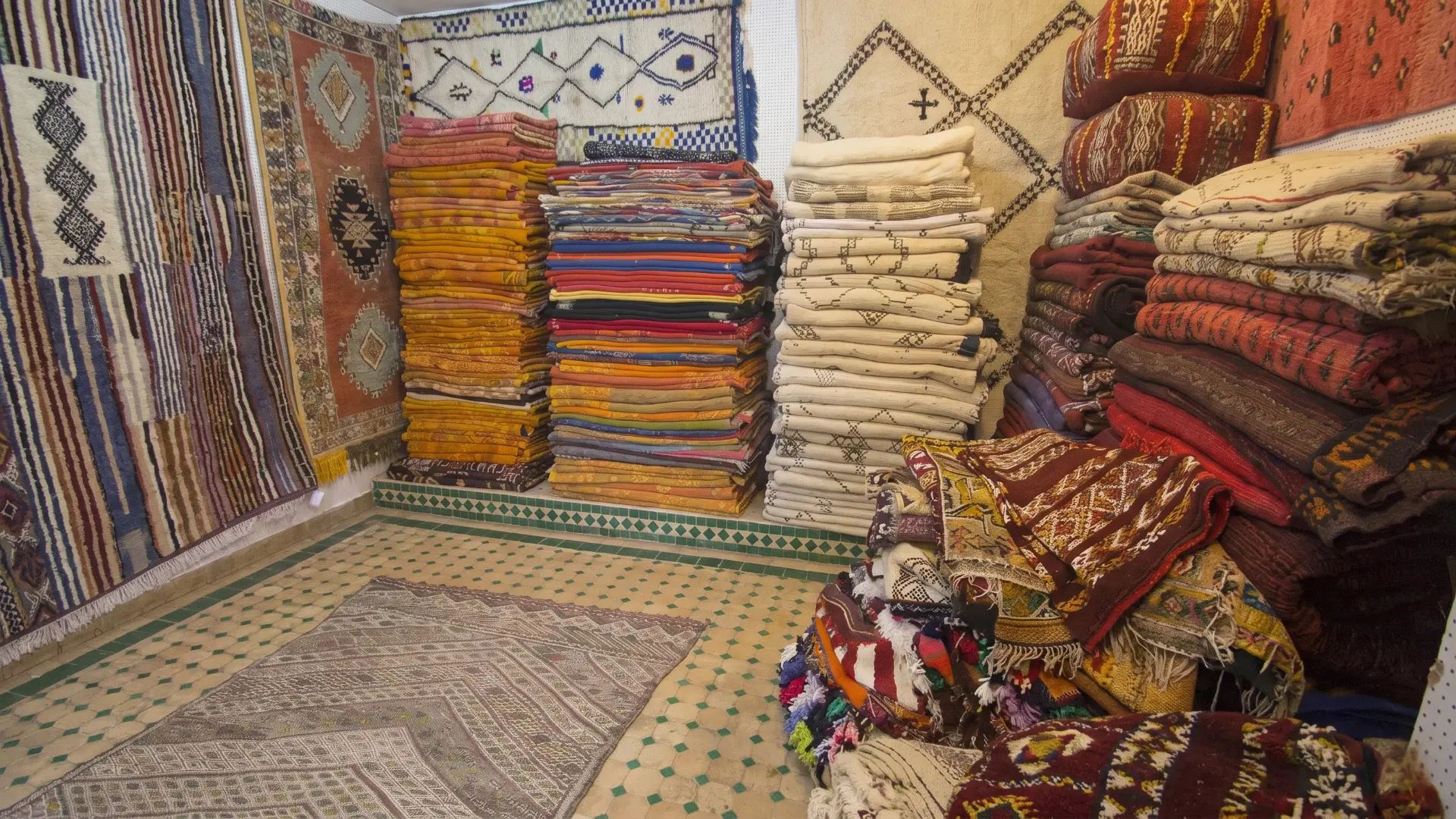 Stacks of vibrant handmade Berber rugs and textiles in a traditional shop in the Fez Medina Morocco