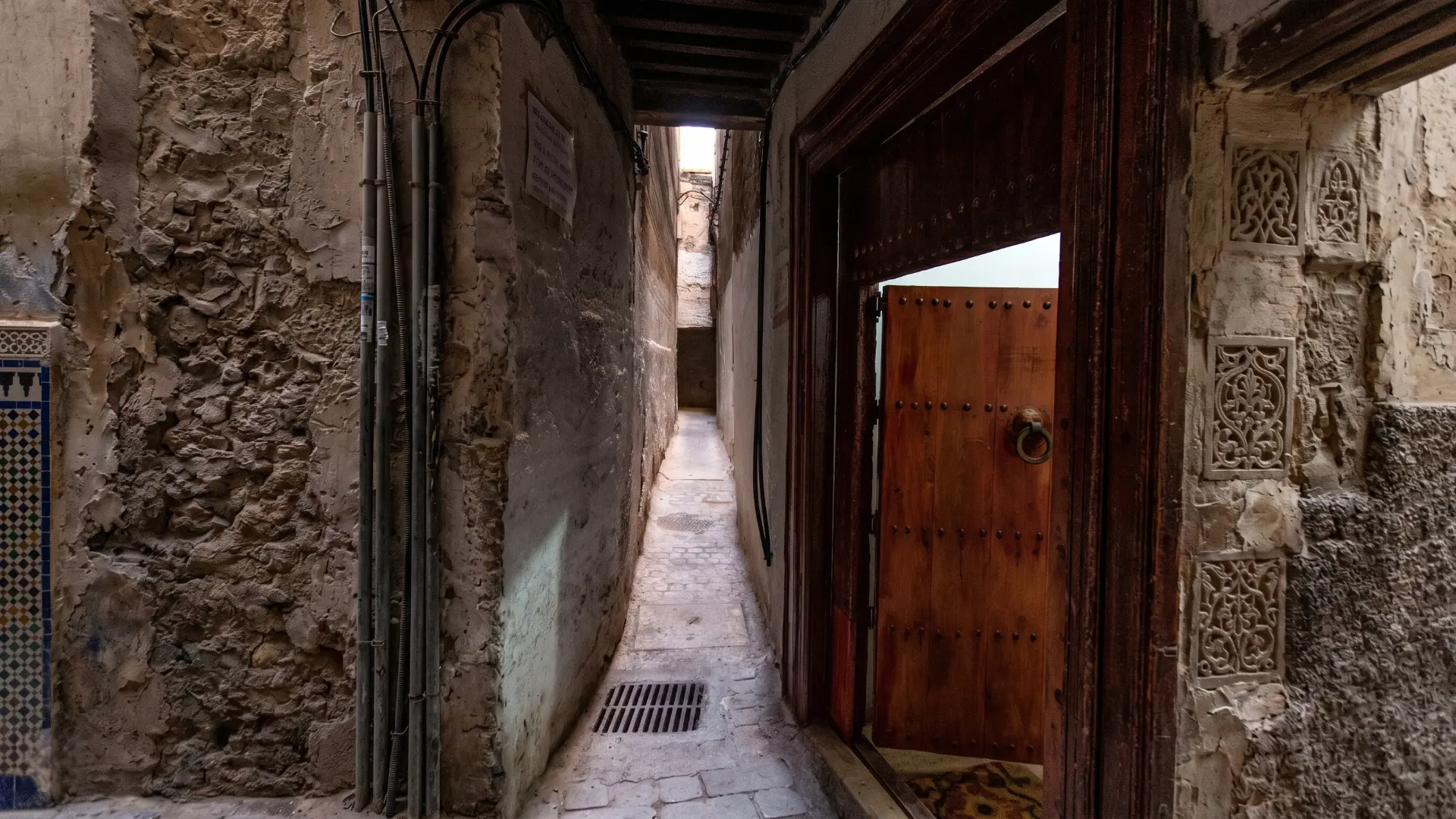 Charming narrow stone alleyway in the old Fez Medina with traditional carved wooden door
